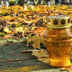 Znicz na cmentarzu w Radomiu, wśród jesiennych liści. Zastanawiasz się, ile kosztuje kremacja w Radomiu?