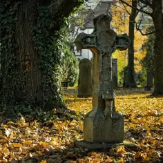 Kamienny krzyż na cmentarzu, jesienią. Czy można sprzedać miejsce na cmentarzu? Pytanie to zadaje sobie wielu, patrząc na te zadumane nagrobki.