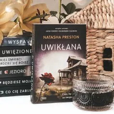 Stos książek z tytułem "Jakiej śmierci najbardziej się boisz", kwiaty, koszyk i kubek z napojem.