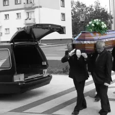 Pogrzebowa karawan i trzej mężczyźni niosący trumnę z kwiatami. Ostatnio odeszli.