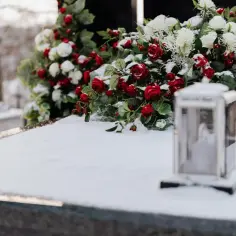 Wieniec z czerwonych róż i białych chryzantem na śniegu. Pamięć o tych, co odeszli.