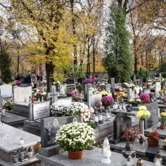 Jesień na cmentarzu komunalnym w Katowicach. Ludzie odwiedzają groby, składają kwiaty i zapalają znicze.