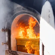 Złota trumna w płomieniach w piecu kremacyjnym.