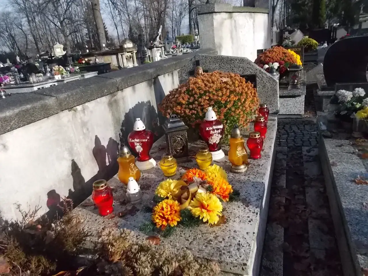 Nagrobek na cmentarzu w Nowym Sączu, ozdobiony zniczami i kwiatami. Grobonet Nowy Sącz.