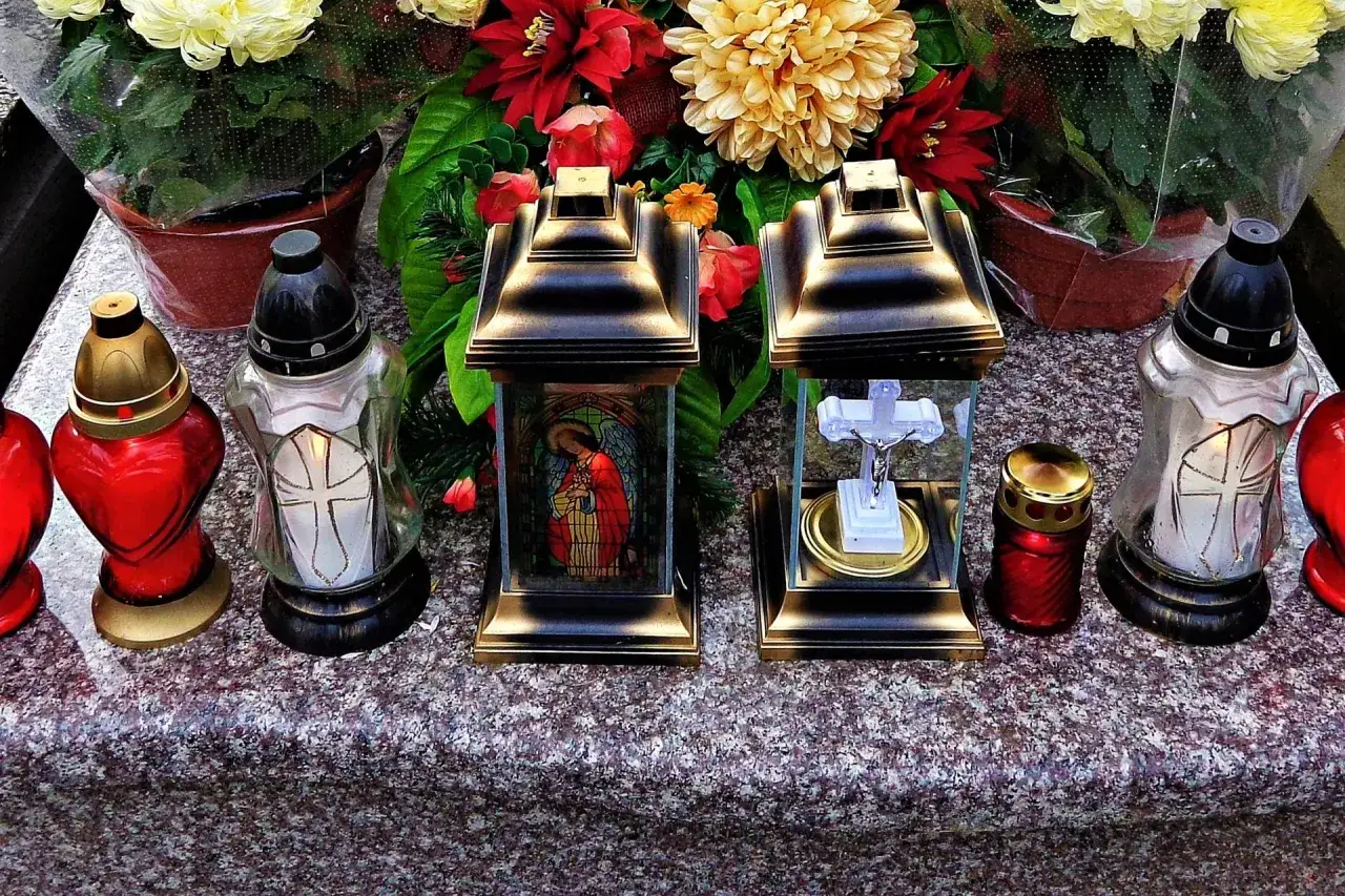 Na grobie stoją znicze i kwiaty. Pytanie, czy można zapalić znicz w dniu pogrzebu, jest tu symbolicznie odpowiedzią.