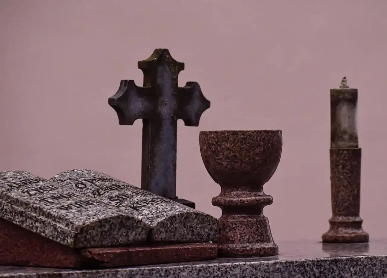 Kamienna księga, krzyż i kielich wskazują, kto jest właścicielem grobu.