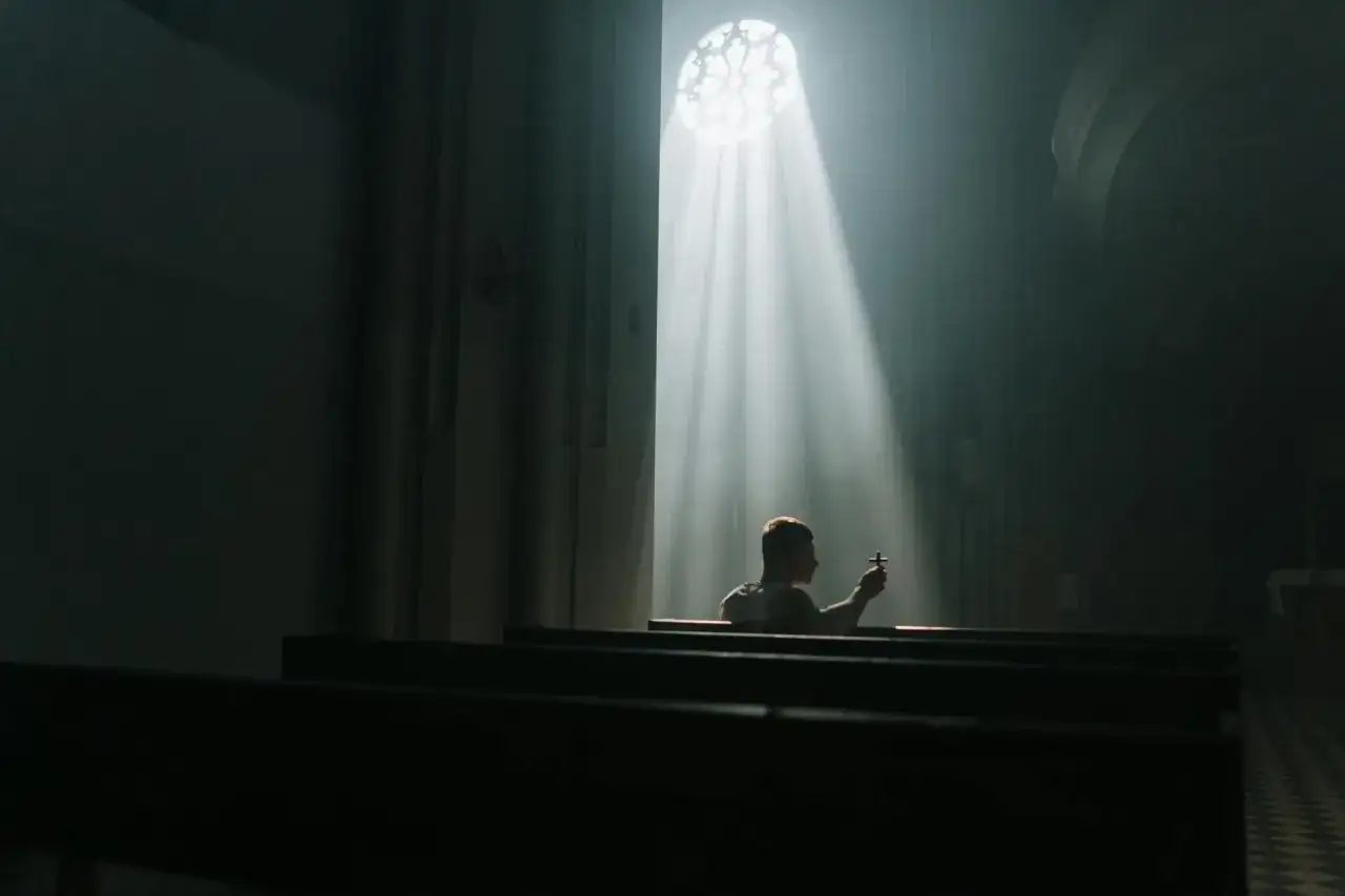 Osoba modląca się w kościele, symbolizująca nadzieję i zaufanie